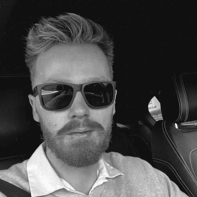 Jordan Brookes, in a black-and-white photo, bearded and wearing sunglasses